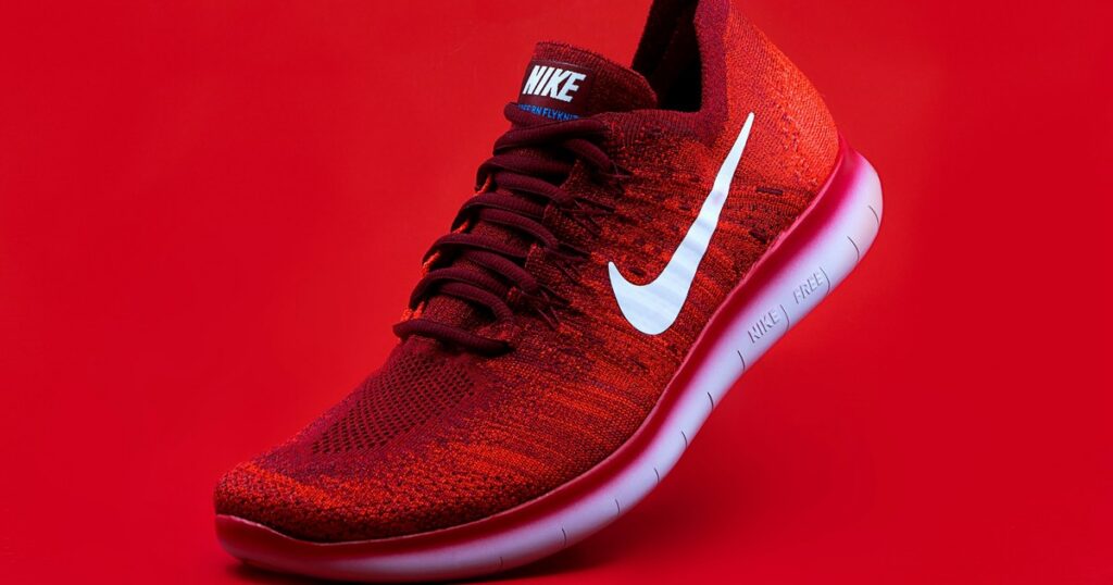 A pair of worn running shoes on a hardwood floor near a sunlit window — the quiet equipment of a daily practice.